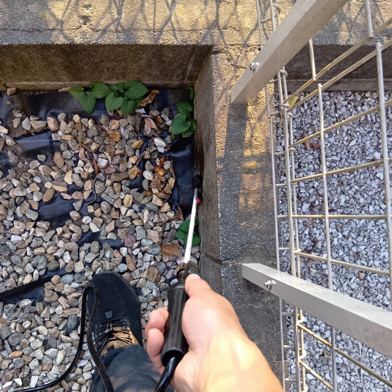 砂利下の地面に忌避剤を散布する様子