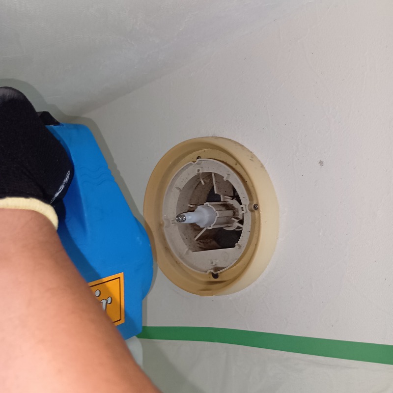 換気扇を取り外し内部に除菌剤を噴霧する様子