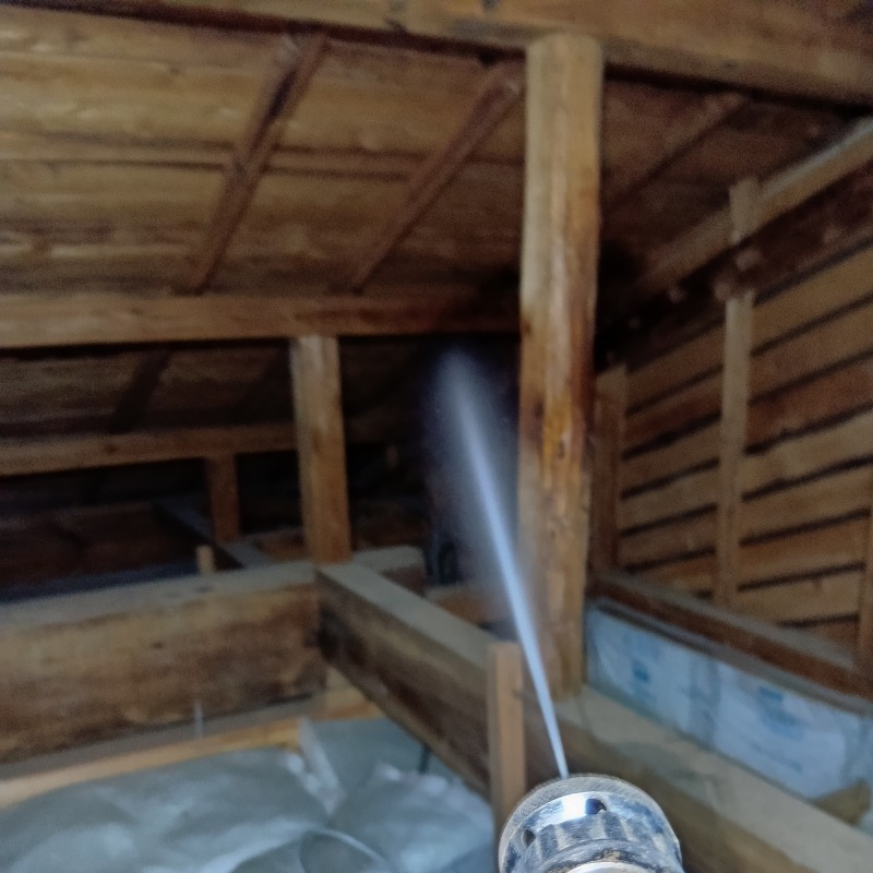 屋根裏の木部にシロアリ駆除剤を散布する様子