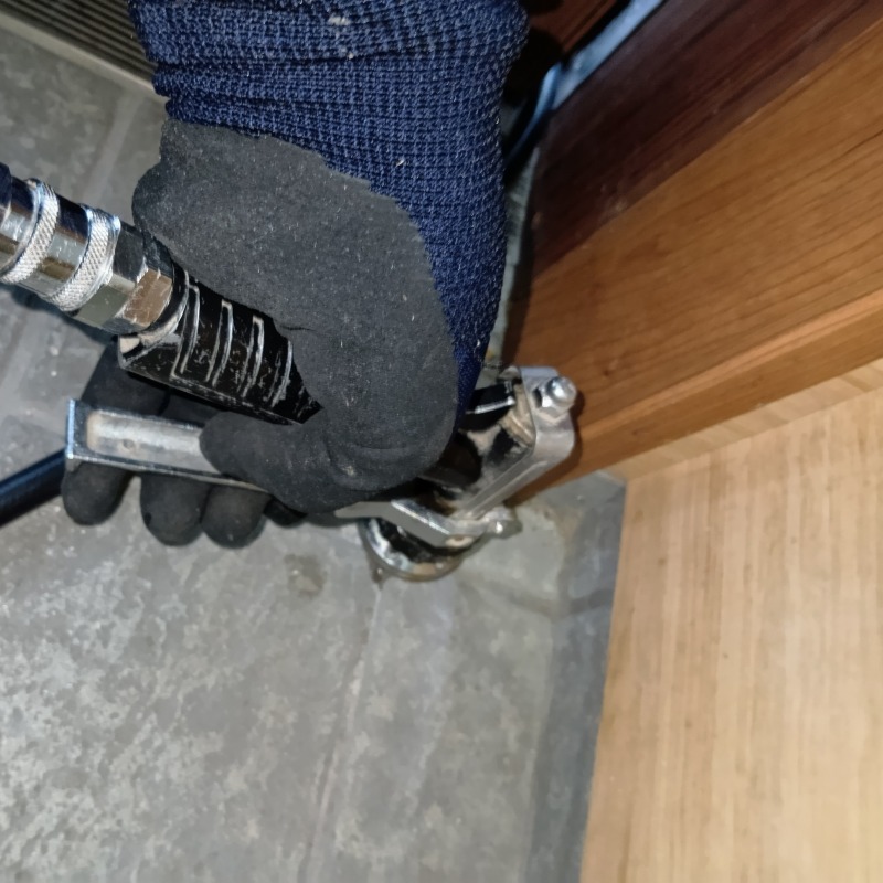 玄関の床にシロアリ駆除剤を注入する様子