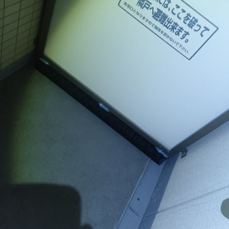 ベランダの仕切り板下部に防鳥ネットを設置した様子