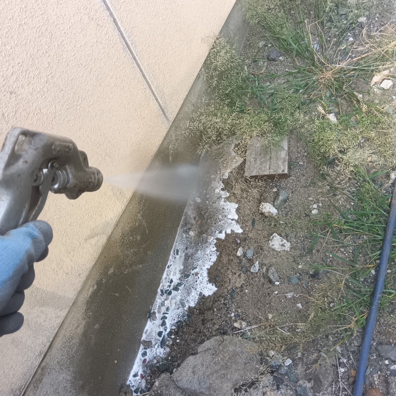 建物外周の地面にシロアリ駆除剤を散布する様子