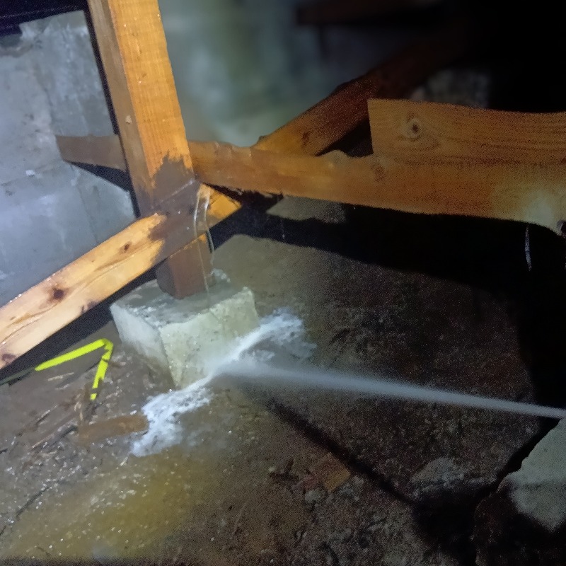 床下の束石まわりにシロアリ駆除剤を散布する様子