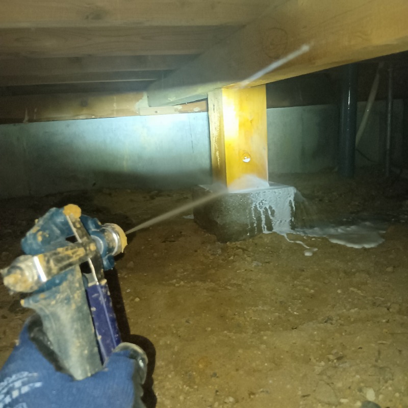 床下の地面や土台部分にシロアリ駆除剤を散布する様子