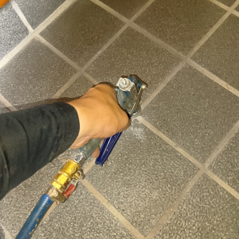 玄関床に穴を開けてシロアリ駆除剤を注入する様子