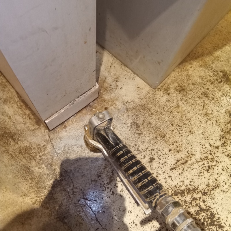 床のひび割れからシロアリ駆除剤を注入する様子