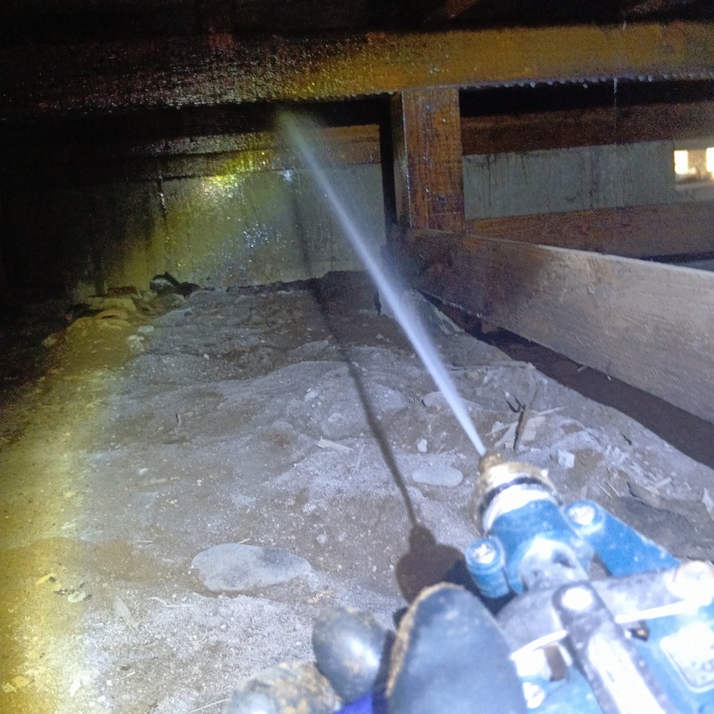 床下木部に防蟻剤を吹き付ける様子