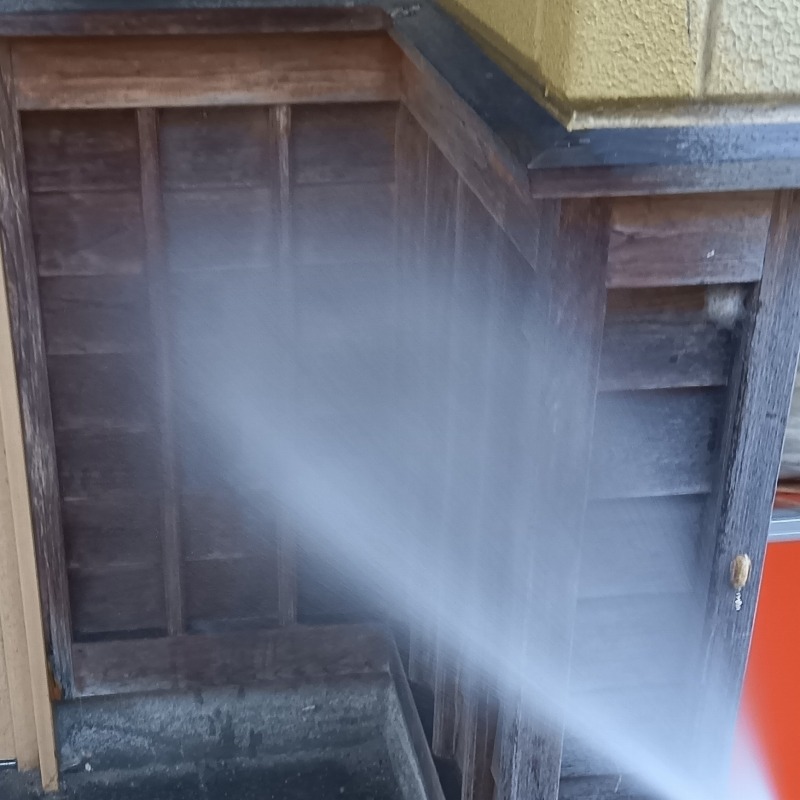 玄関の木部にシロアリ駆除剤を吹き付ける様子