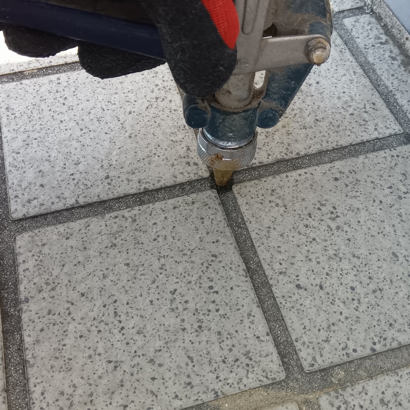 タイルの目地から薬剤を注入する様子