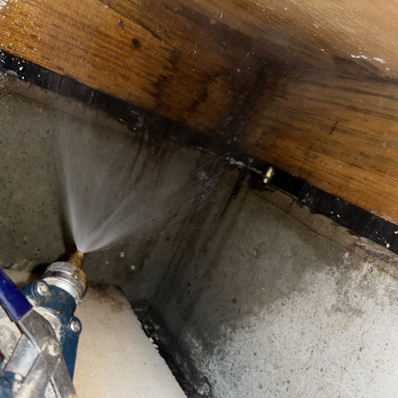 床下木部にシロアリ駆除剤を散布する様子