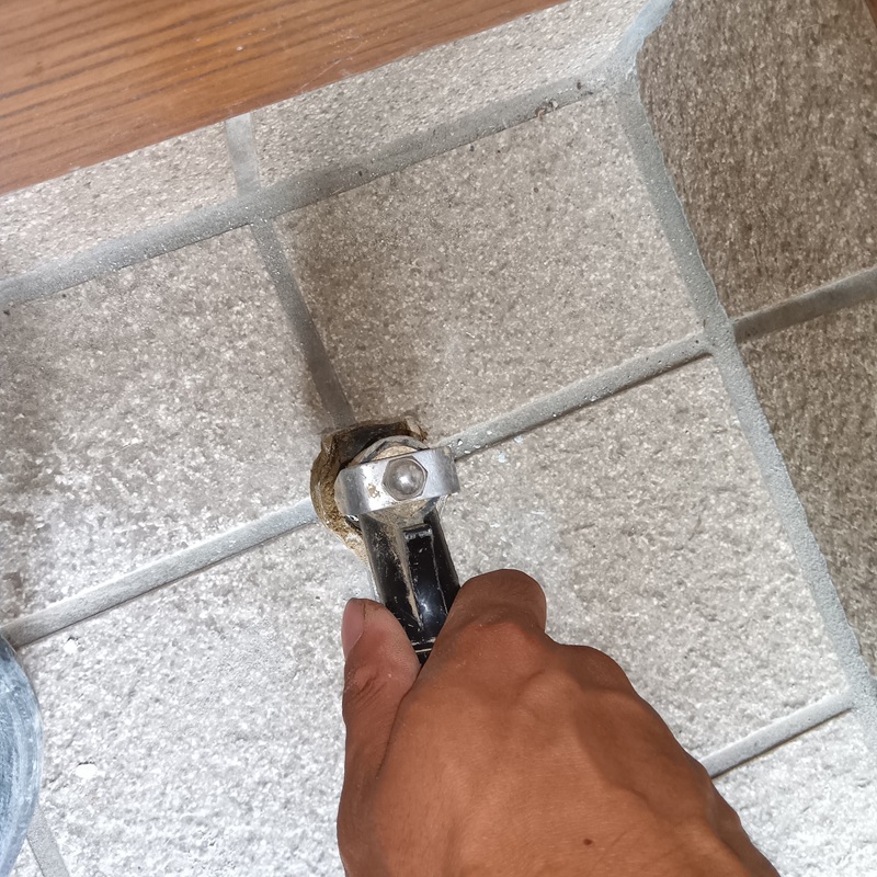 玄関の床にシロアリ駆除剤を注入する様子