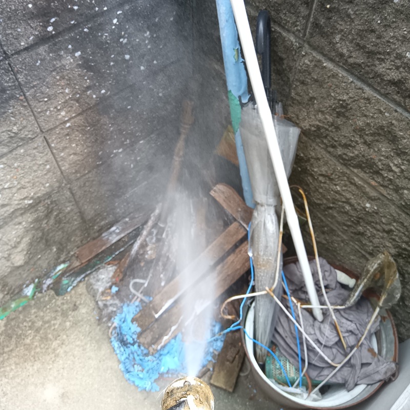 屋外の廃材にシロアリ駆除剤を散布する様子