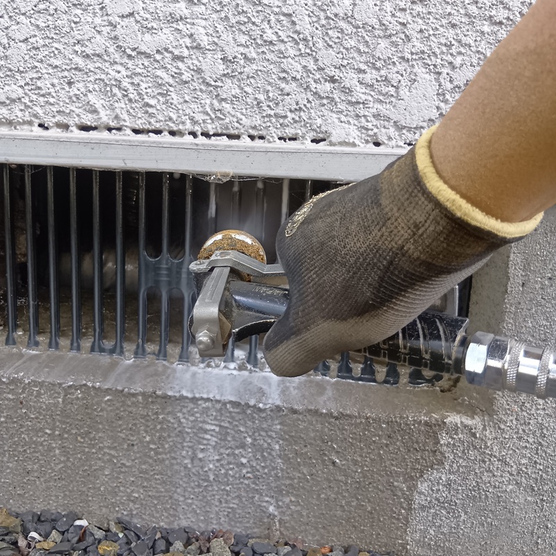 床下通気口から防蟻剤を散布する様子