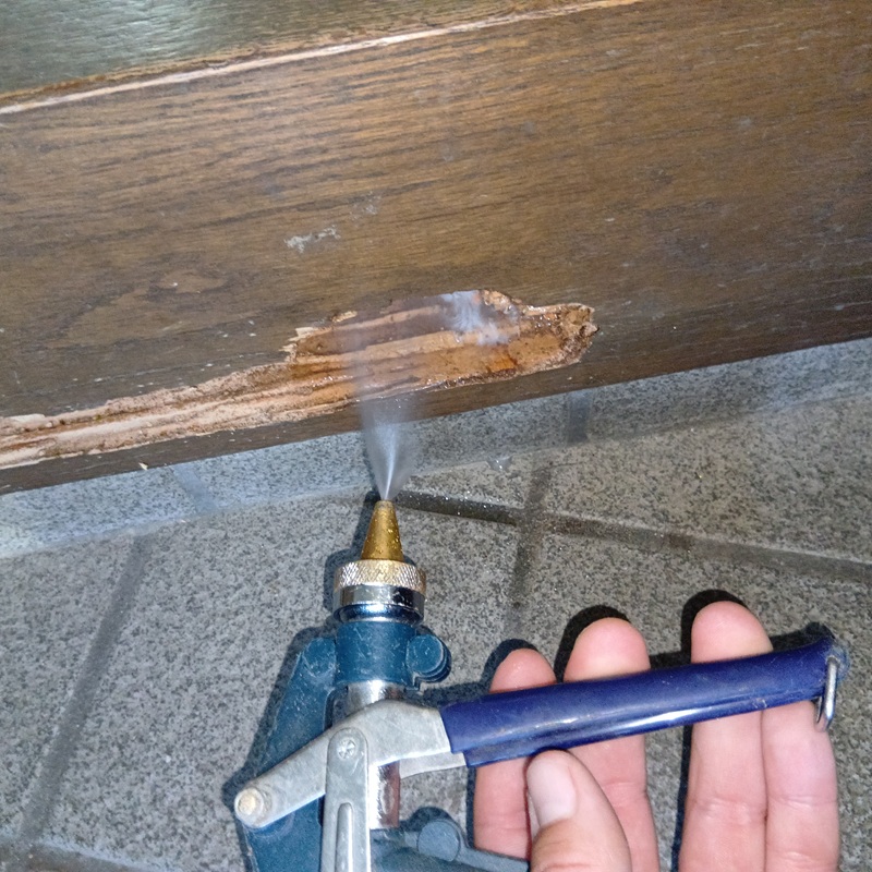 被害を受けた木材にシロアリ駆除剤を吹き付ける様子