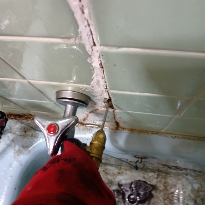 浴室の壁にシロアリ駆除剤を注入する様子