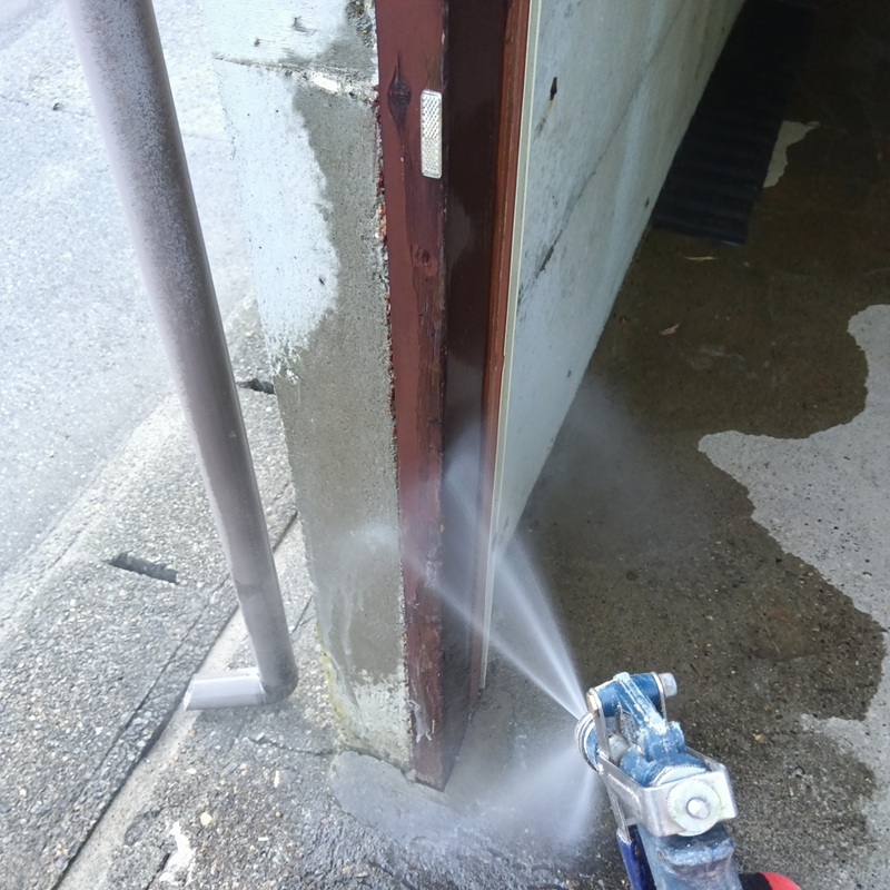 入口の木材にシロアリ駆除剤を吹き付ける様子