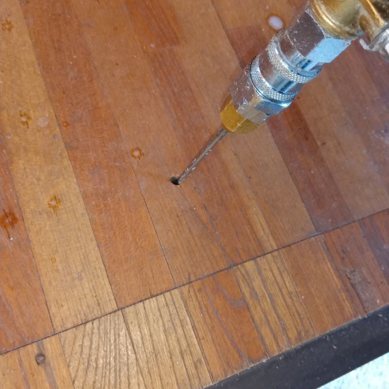 床に穴を開けてシロアリ駆除剤を注入する様子