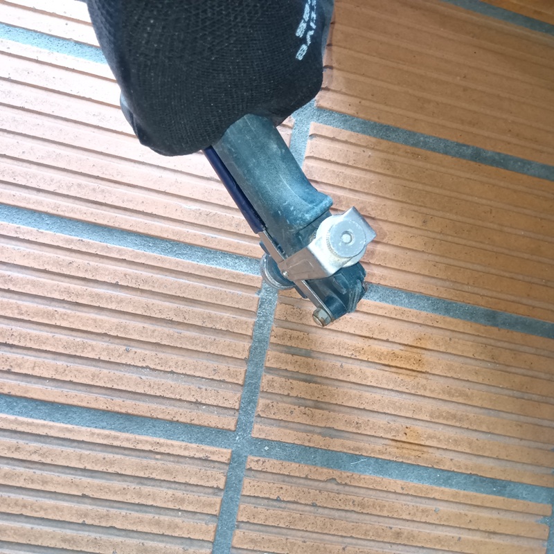 玄関床に穴を開けて薬剤を注入する様子