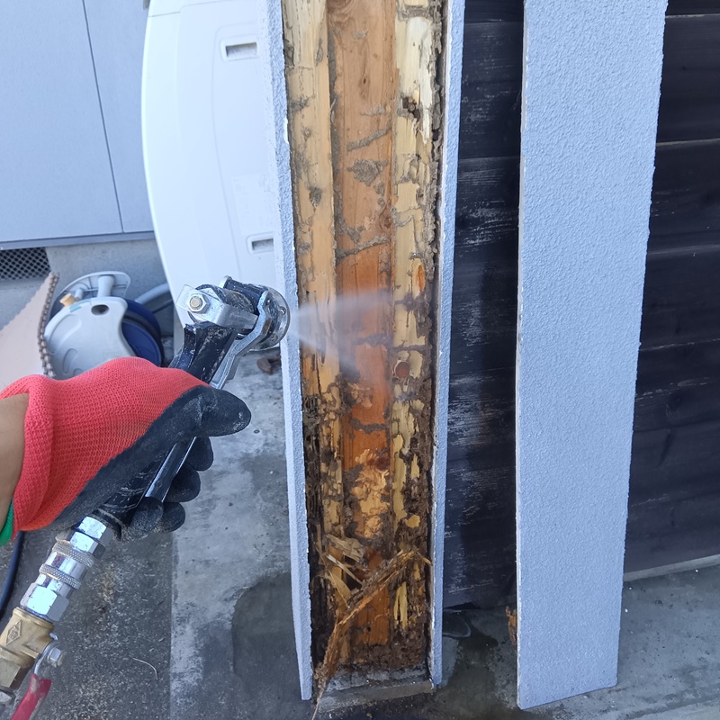 柱の木部に防蟻剤を吹き付けている様子