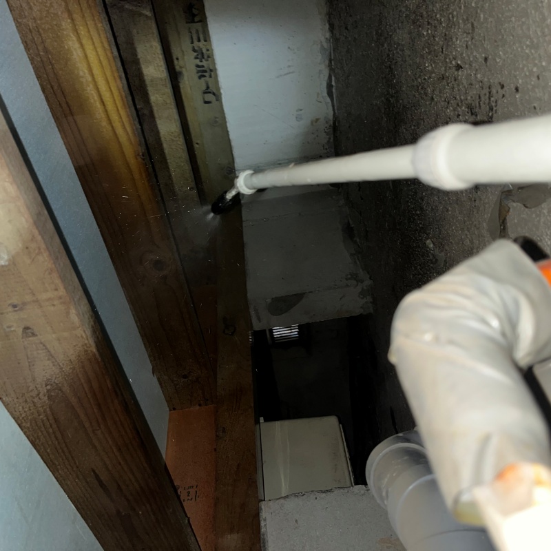 床下の地面にシロアリ駆除剤を散布している様子