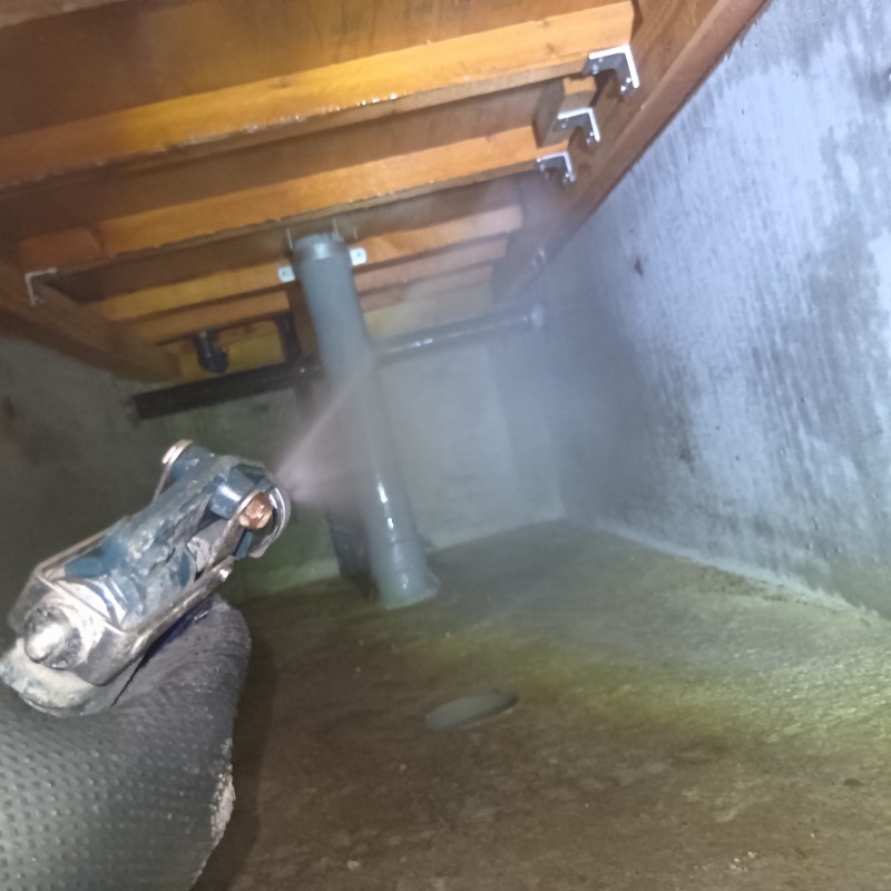 基礎部分にシロアリ駆除剤を吹きつけている様子