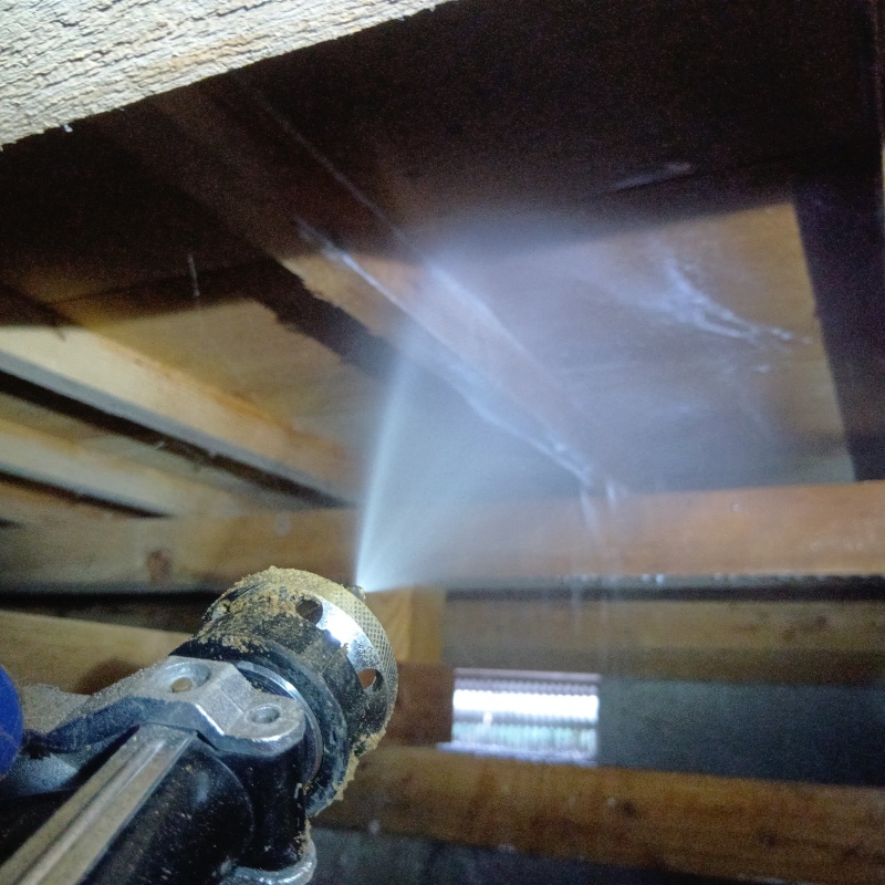 床下の木材にシロアリ駆除剤を吹きつけている様子