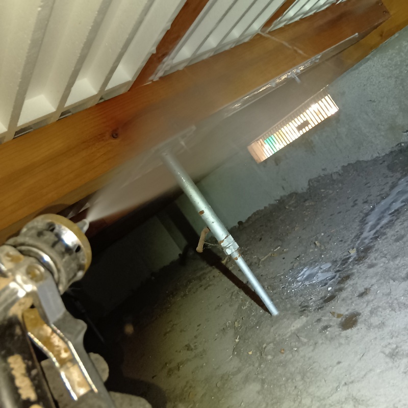 床下換気口まわりにシロアリ駆除剤を散布している様子