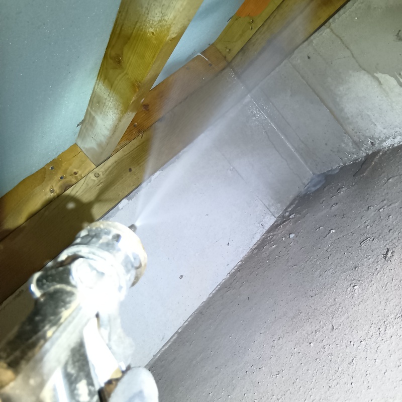 床下のコンクリート部分に防蟻剤を吹きつけている様子