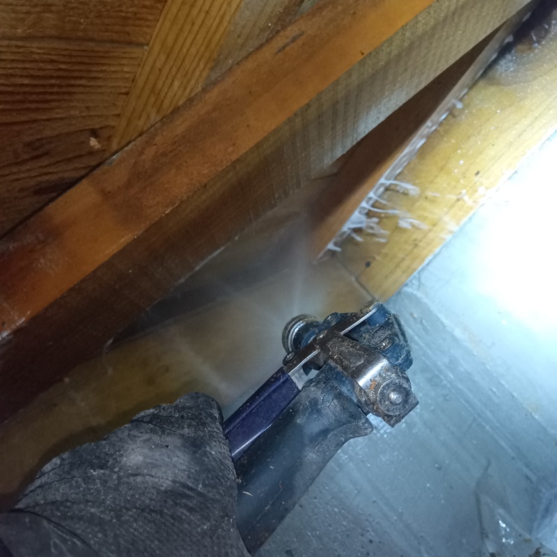 床下の木材にシロアリ駆除剤を散布している様子