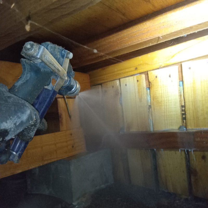 床下の木材にシロアリ駆除剤を散布している様子