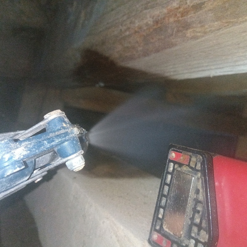 床下の木材にシロアリ駆除剤を吹きつけている様子