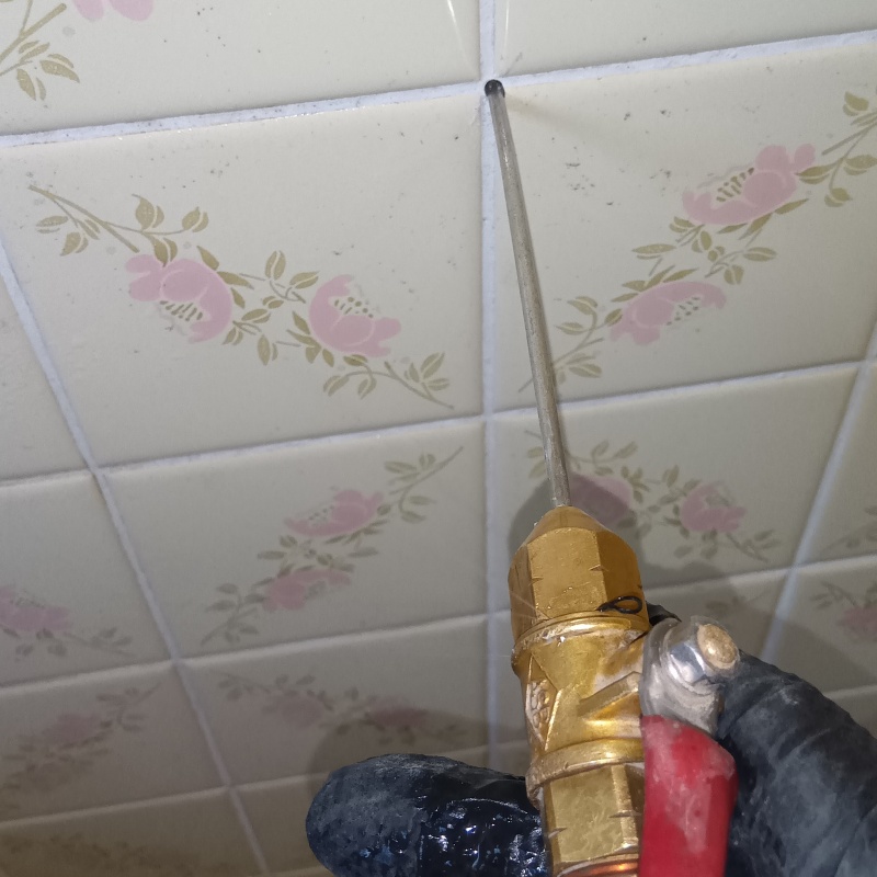 浴室の壁にシロアリ駆除剤を注入している様子