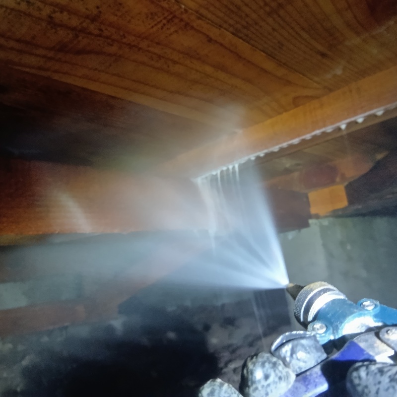 床下の木材に防蟻剤を散布している様子