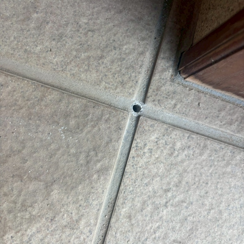 玄関床のタイルの目地に穴を開けている様子