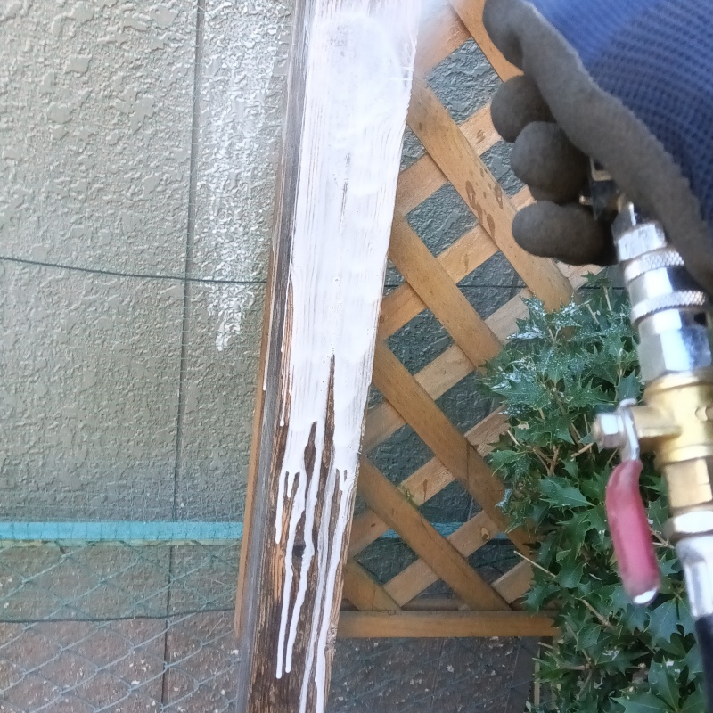 木製の柵にシロアリ駆除剤を吹き付けている様子