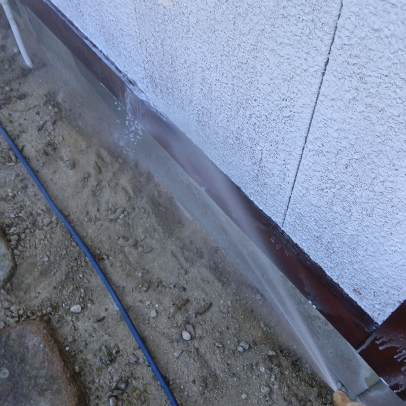 建物外周の土壌にシロアリ駆除剤を散布する様子