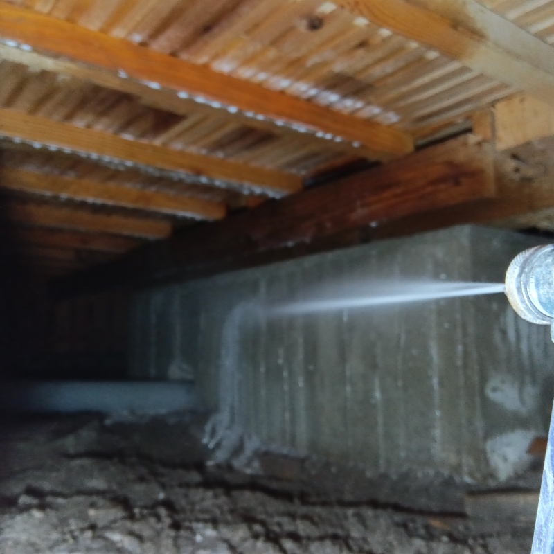 床下の基礎部分にシロアリ駆除剤を散布する様子