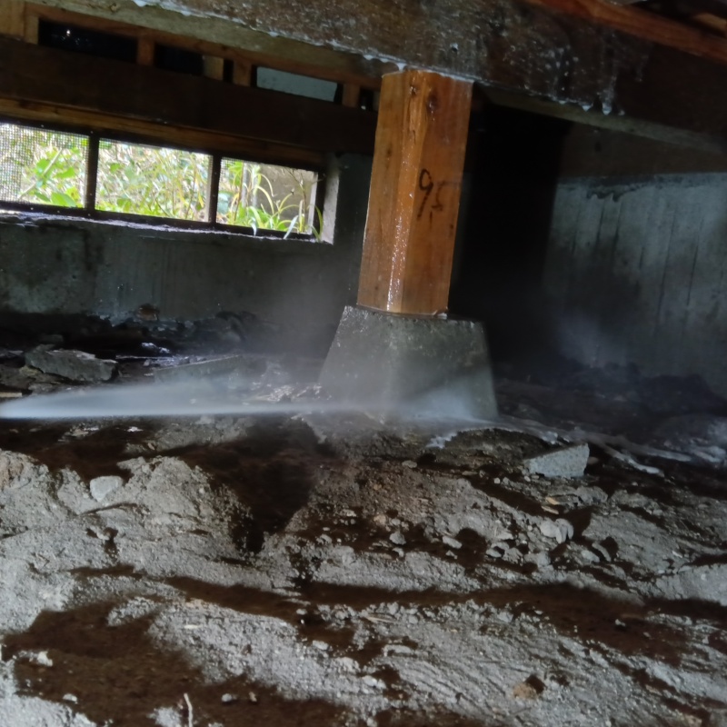 束石にシロアリ駆除剤を吹き付けている様子