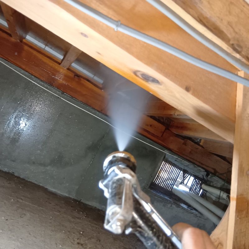 床下木材に防蟻剤を吹きつけている様子