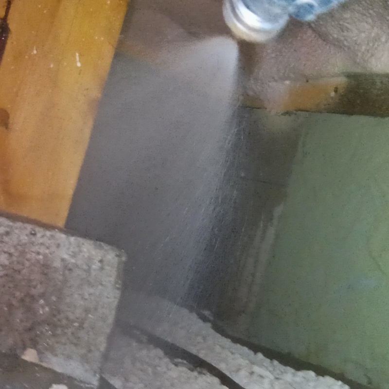 束石まわりに防蟻剤を吹きつけている様子