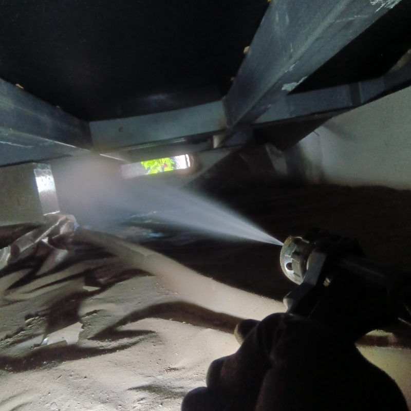 床下の基礎にシロアリ駆除剤を吹き付けている様子