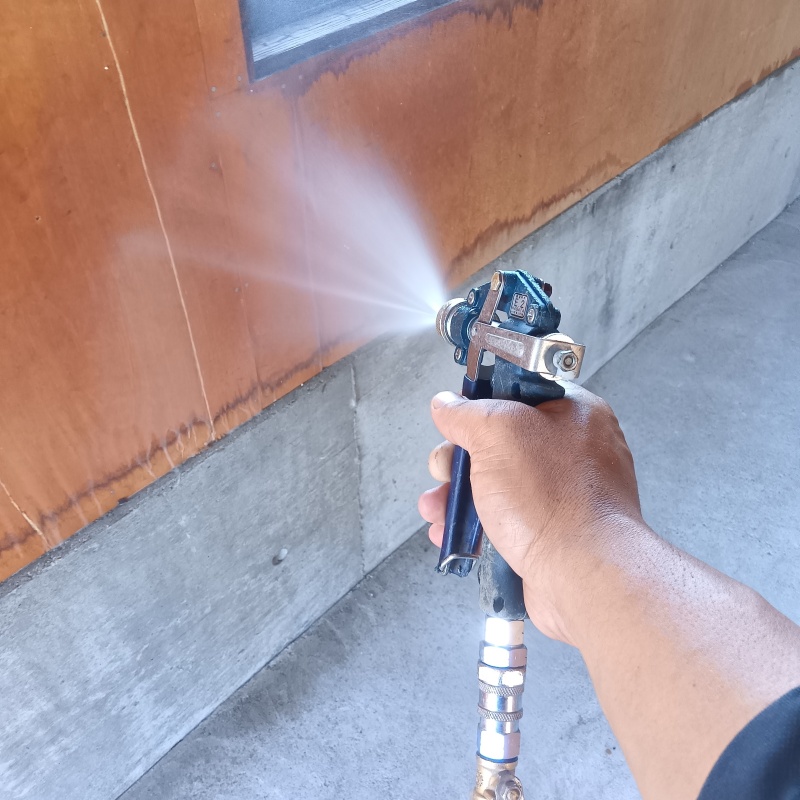 木製の壁材にシロアリ駆除剤を吹き付けている様子