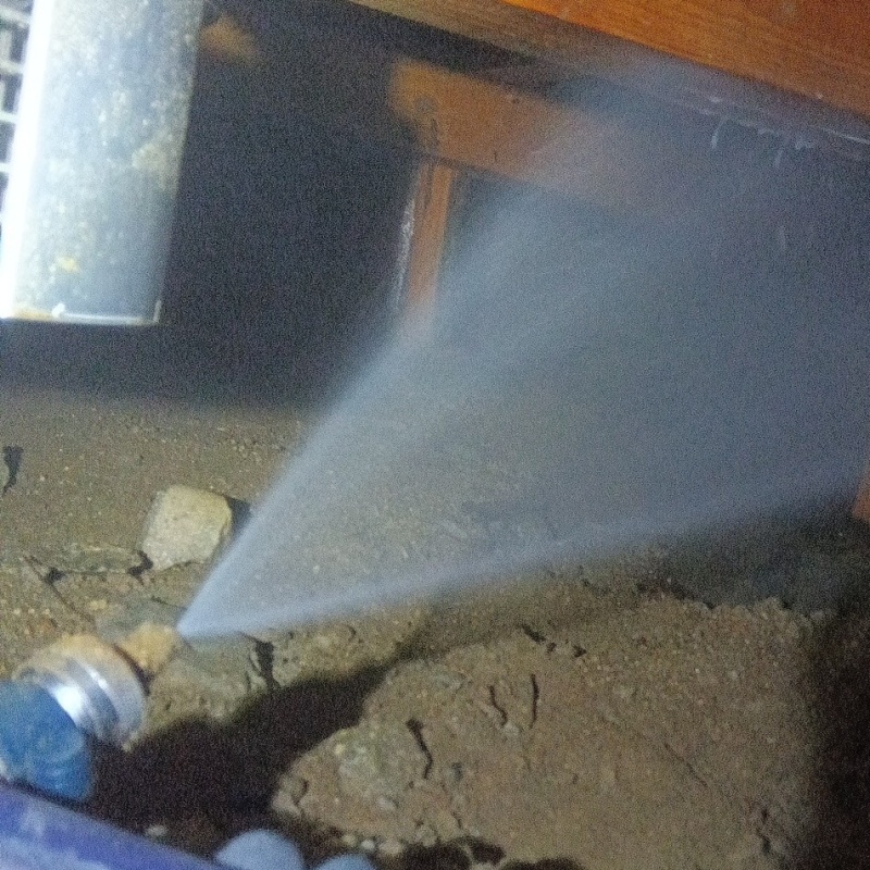 床下木材にシロアリ駆除剤を吹き付ける様子