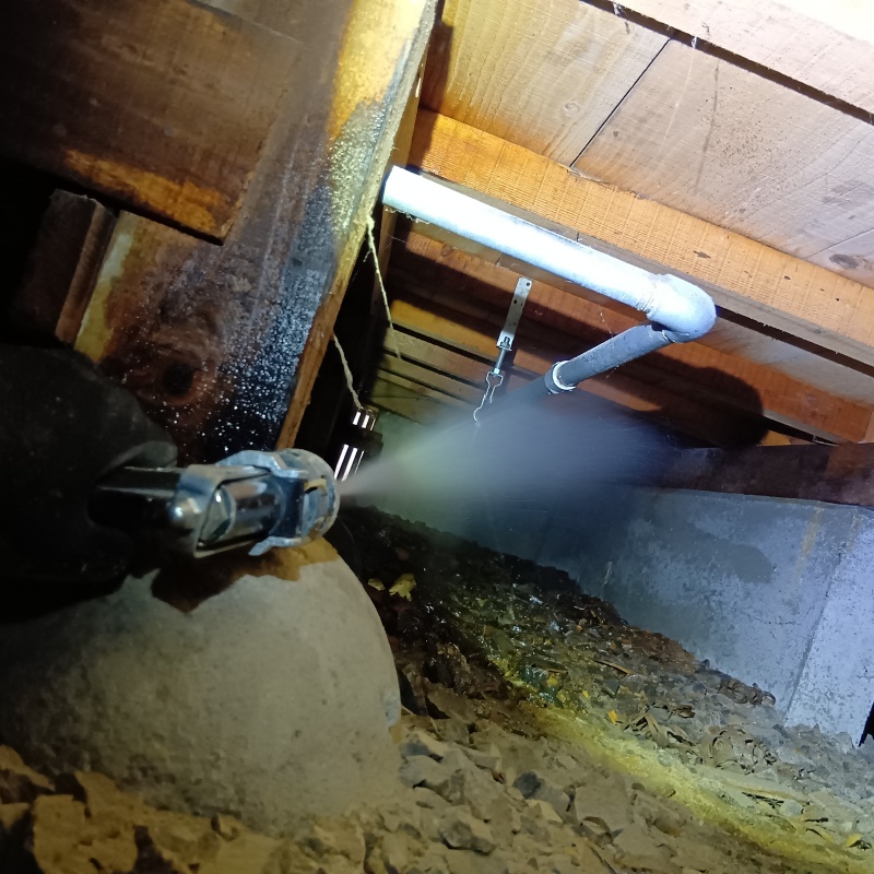床下木材にシロアリ駆除剤を吹き付ける様子