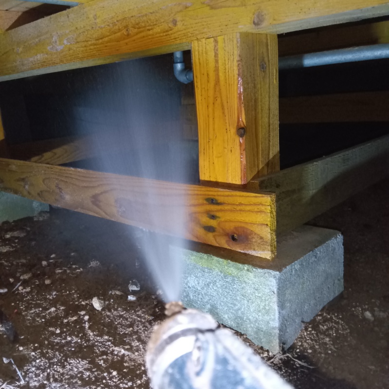 床下木材に防蟻剤を吹き付ける様子