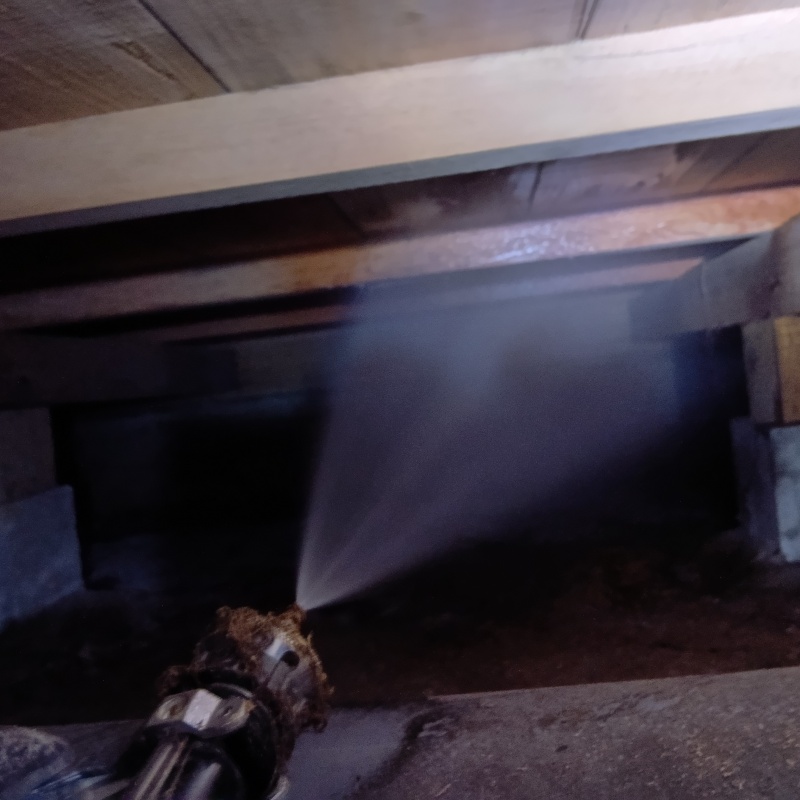 床下木材にシロアリ駆除剤を吹き付ける様子