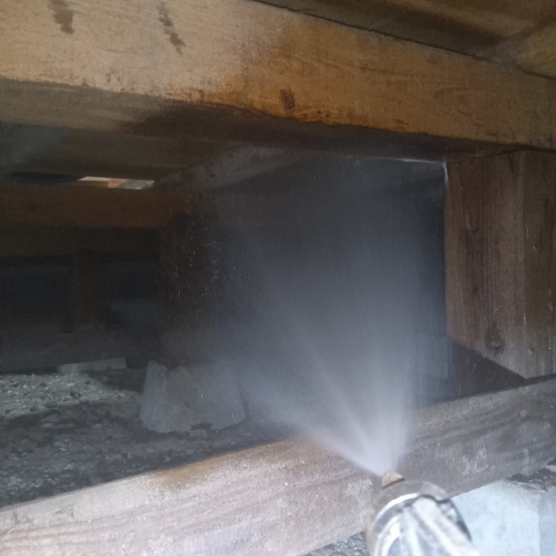 床下木材にシロアリ駆除剤を吹き付ける様子