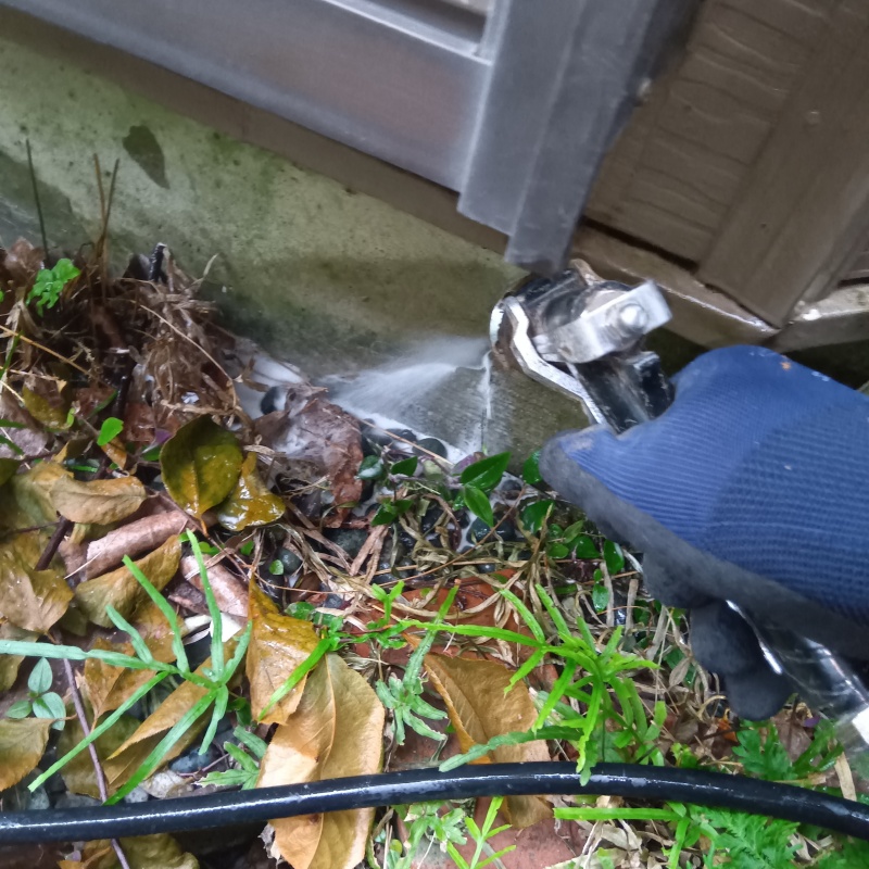 建物外周の土壌にシロアリ駆除剤を吹き付ける様子