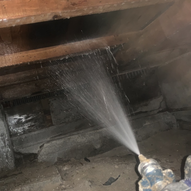 床下の木材にシロアリ駆除剤を散布する様子