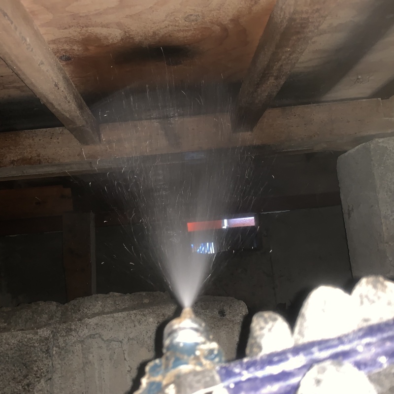 床下の木材にシロアリ駆除剤を散布する様子